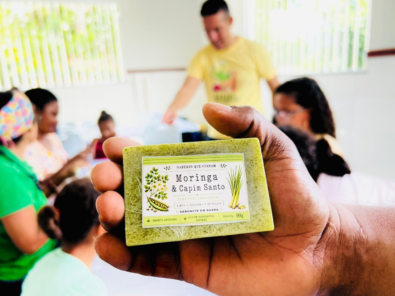 Mão segurando sabonete artesanal de moringa e capim-santo durante atividade da Farmácia Verde